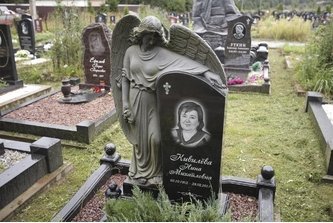 Ангел из черного гранита, обнимающий стелу