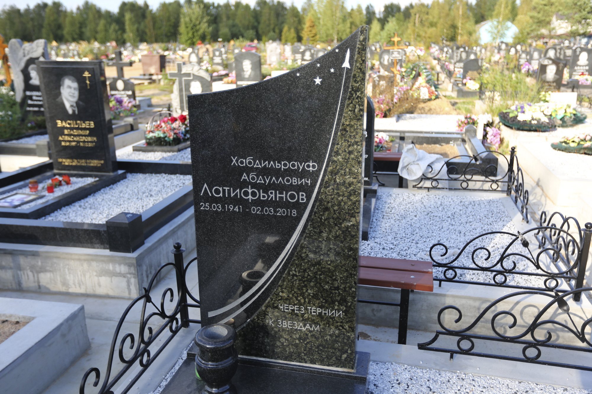 Памятник из чёрного и зелёного гранита с металлической оградой